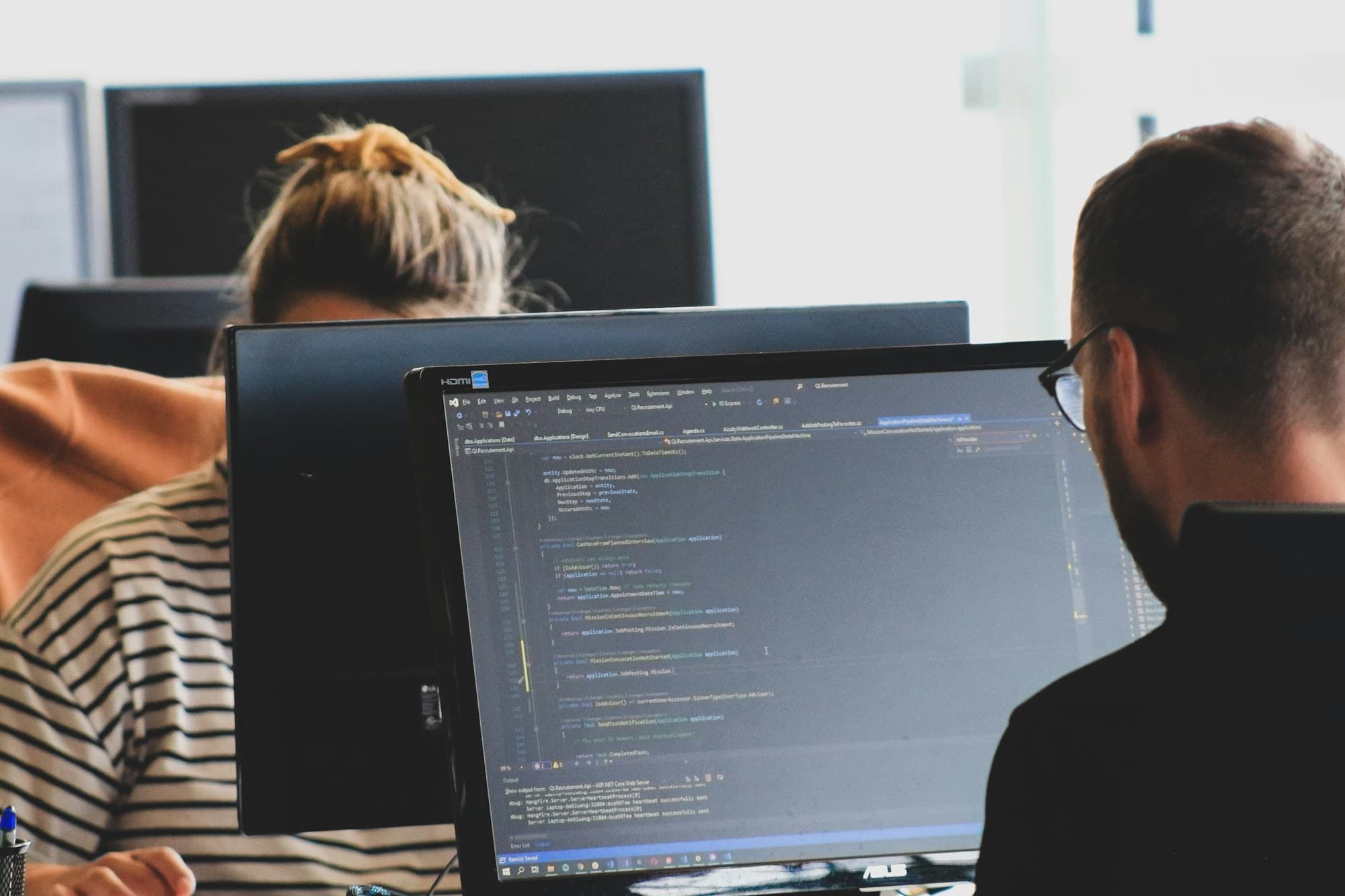 Developers writing code at large monitors